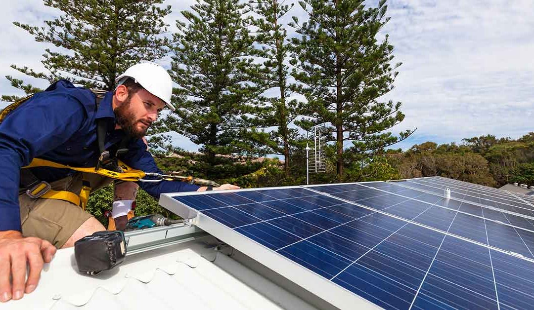 Handwerker montiert Photovoltaikanlage auf Hausdach | Energieautarkes Haus