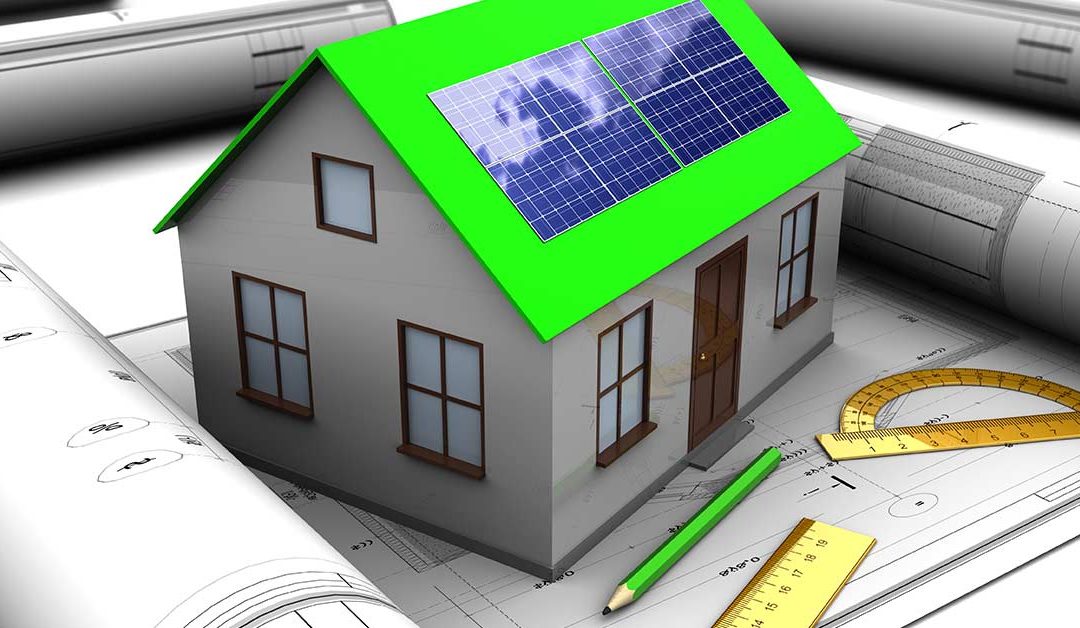 Ein Modell eines Hauses mit grünem Dach und Photovoltaikanlage steht auf einem Bauplan, rundherum liegen weitere Rollen Baupläne, Stifte und Lineale | Energieeffizient bauen