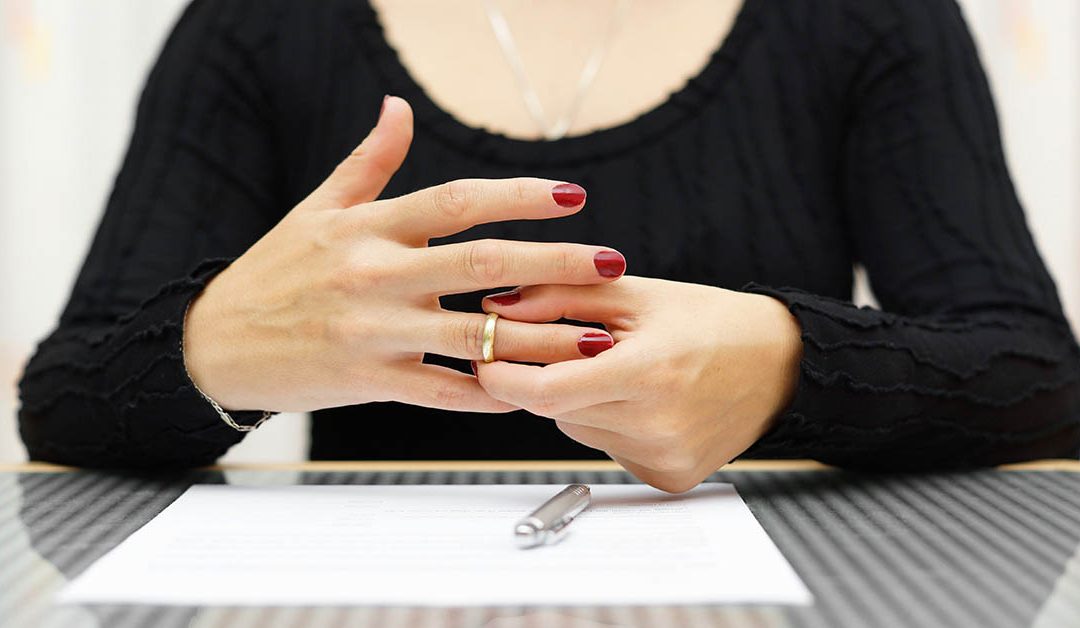 Eine Frau die Ihren Ehering vom Finger zieht - Scheidungsimmobilie
