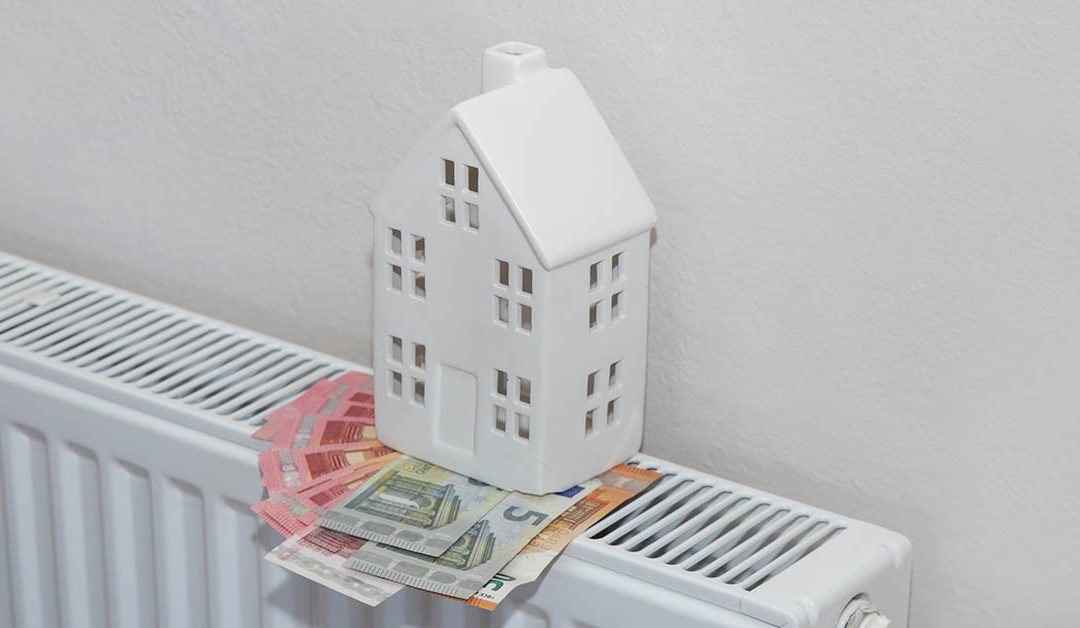 Ein weißes Minihaus auf einer Heizung mit Geldscheinen - Betriebskosten